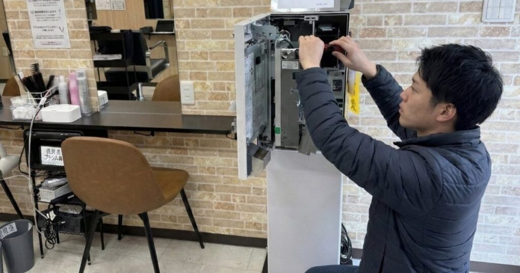 券売機の出張修理に対応するアトラスのスタッフ
