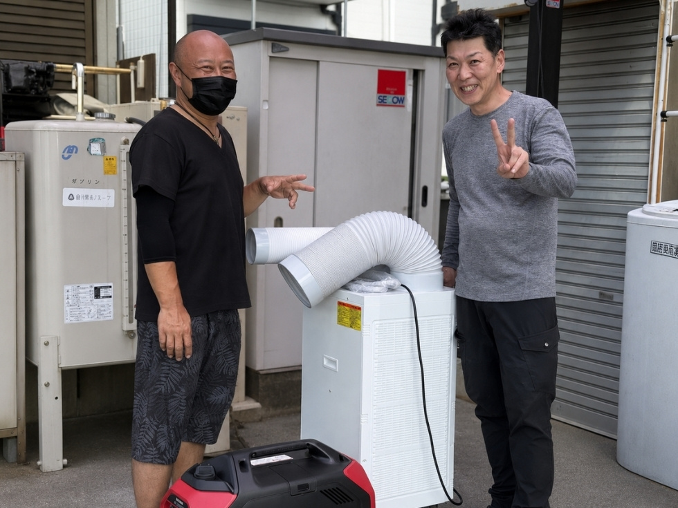 レンタル用スポットクーラーを受け取るお客様とアトラススタッフ