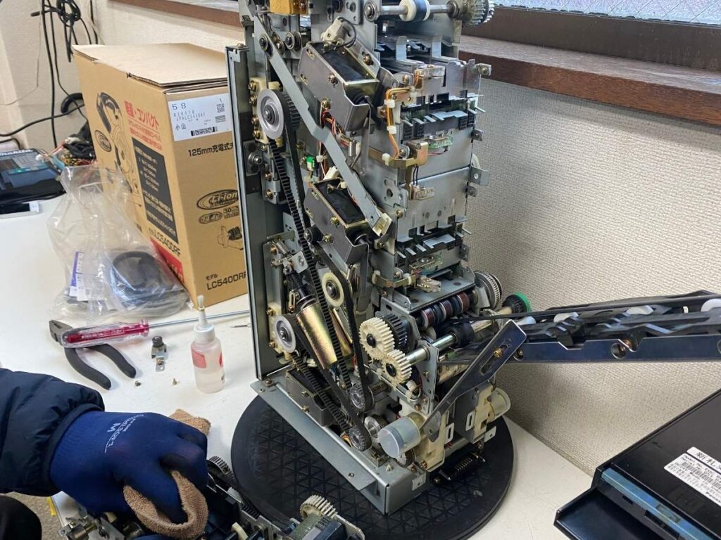 アトラスの修理専門スタッフが両替機の入出金ユニットを分解修理している様子